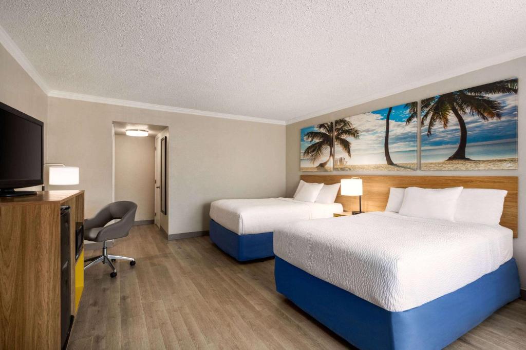 a hotel room with two beds and a flat screen tv at Days Inn by Wyndham Miami Airport North in Miami