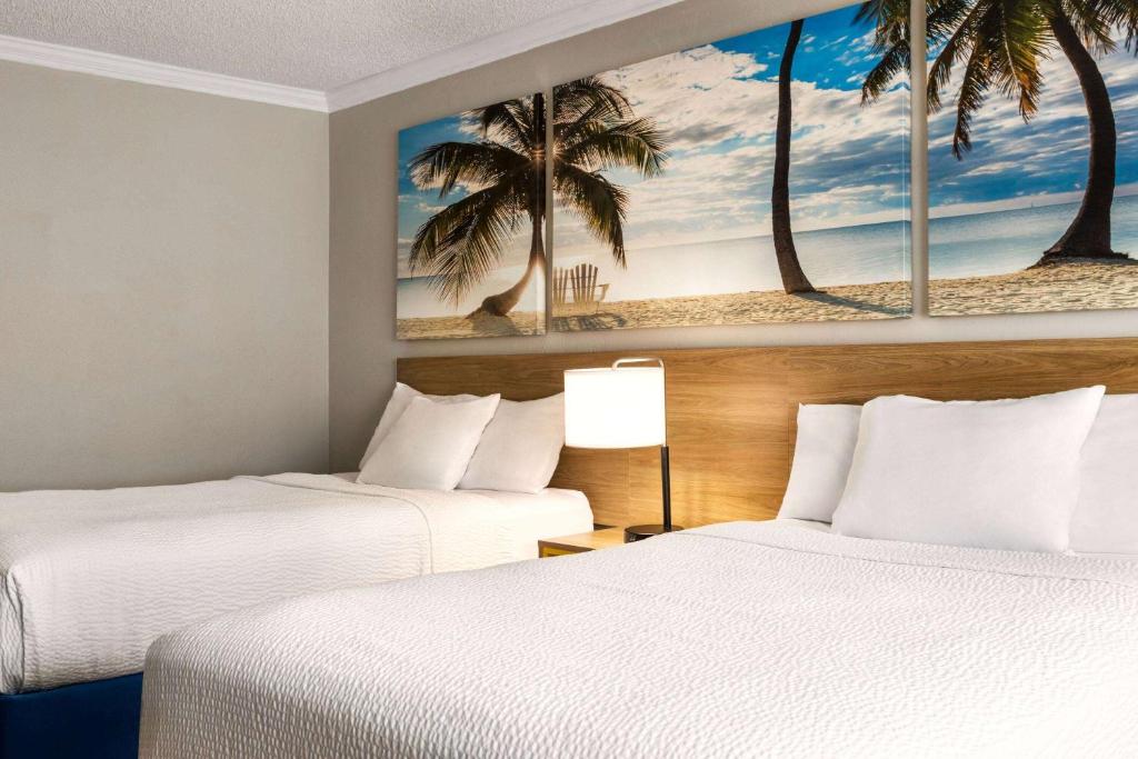 two beds in a hotel room with palm trees at Days Inn by Wyndham Miami Airport North in Miami