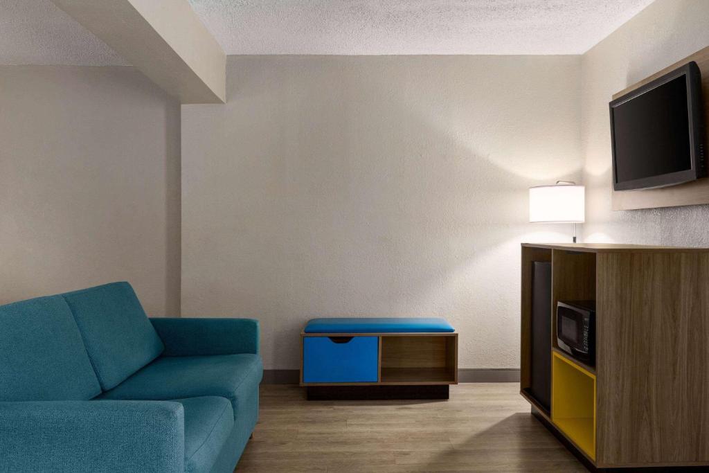 a living room with a blue couch and a tv at Days Inn by Wyndham Miami Airport North in Miami