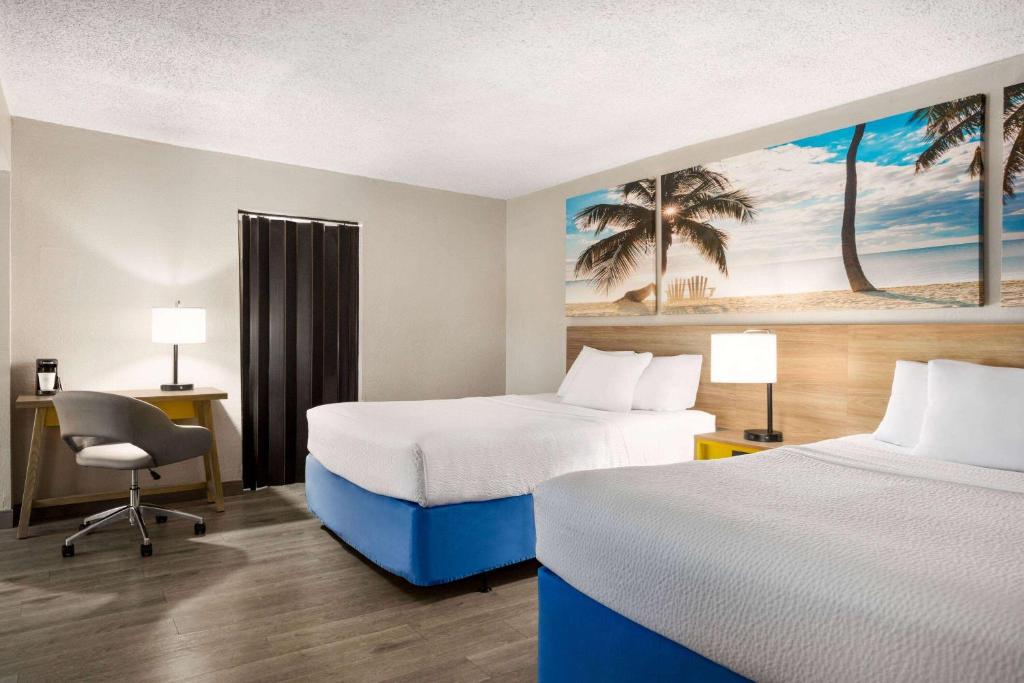 a hotel room with two beds and a desk at Days Inn by Wyndham Miami Airport North in Miami