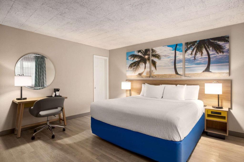a bedroom with a bed and a desk and a chair at Days Inn by Wyndham Miami Airport North in Miami