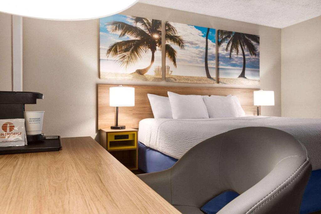 a hotel room with a bed and a desk with a chair at Days Inn by Wyndham Miami Airport North in Miami