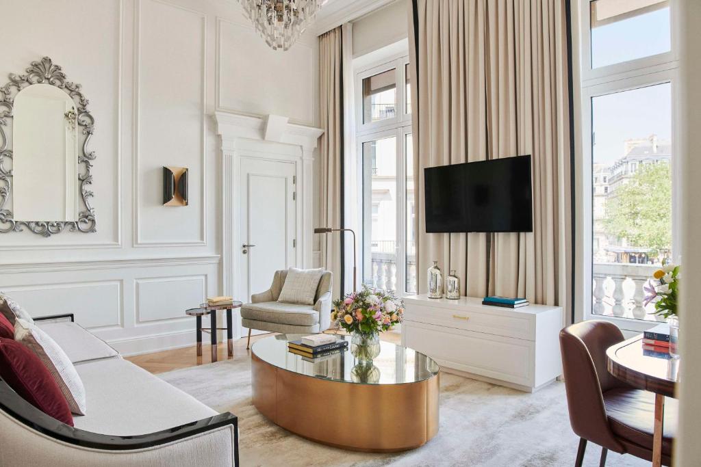a living room with a coffee table and a tv at Hôtel du Louvre, in The Unbound Collection by Hyatt in Paris