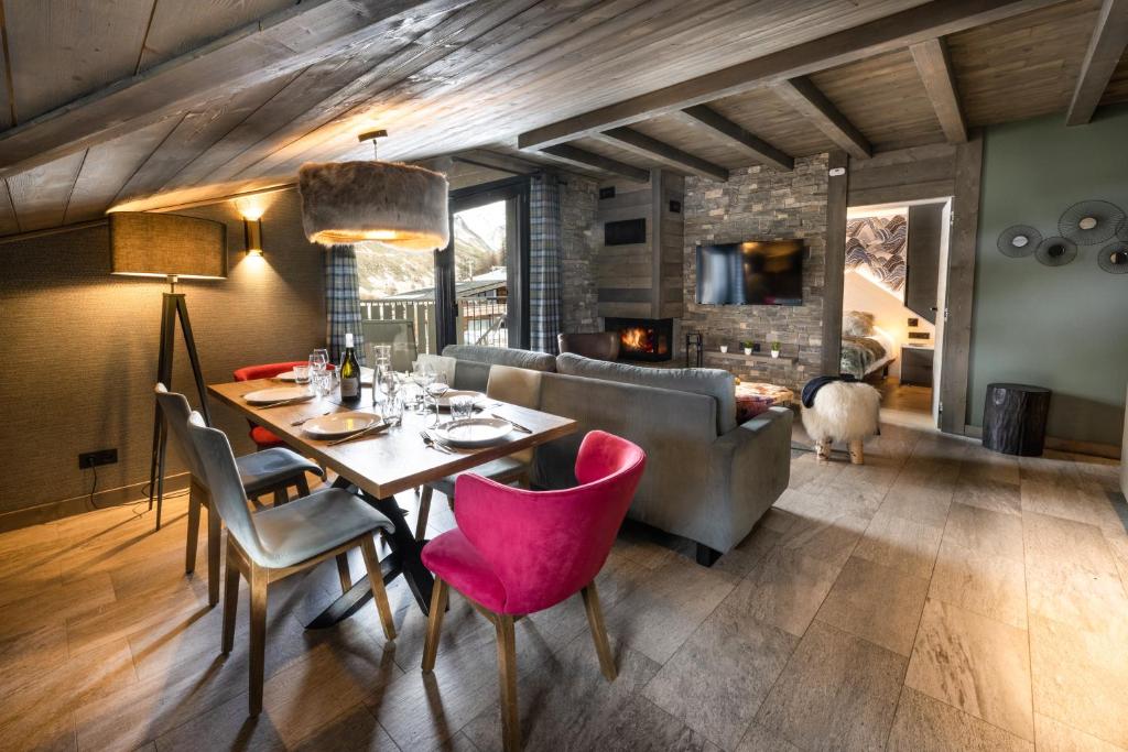 une salle à manger avec une table, des chaises et un canapé dans l'établissement Chalets Izia - Village Montana, à Val dʼIsère
