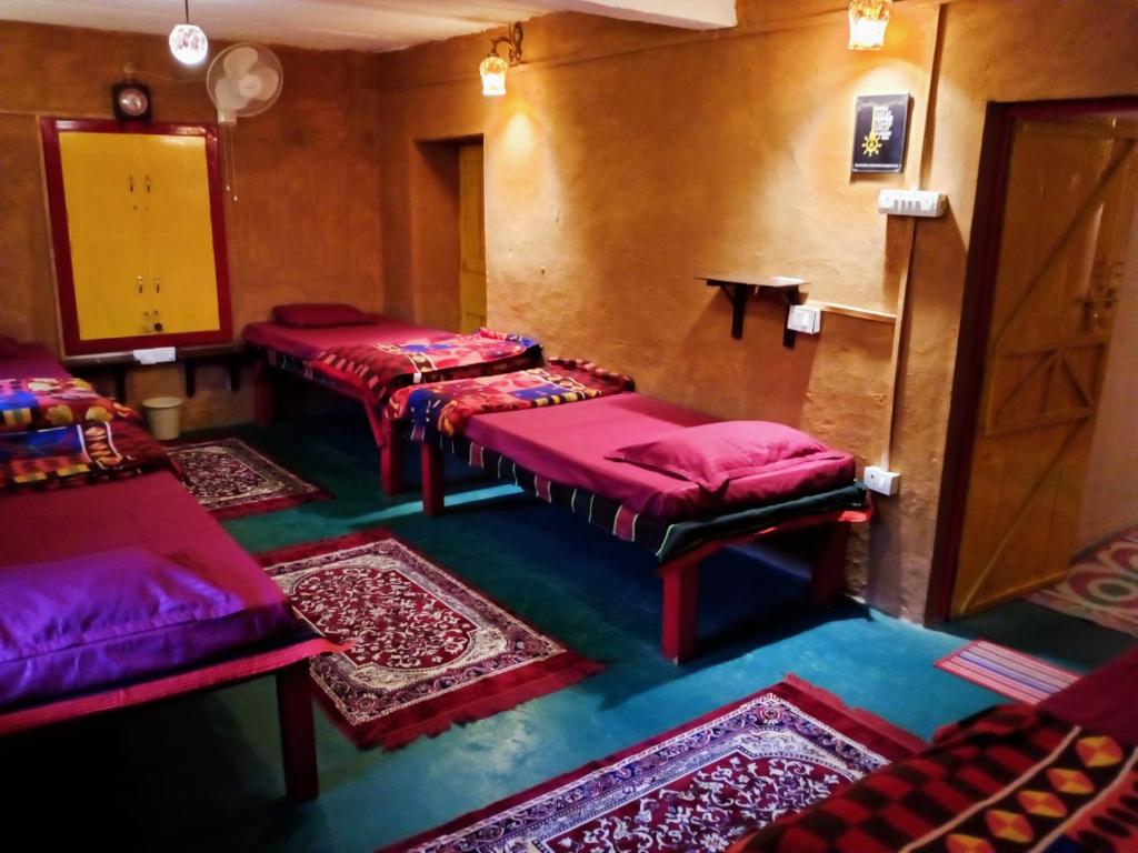 a room with four beds and rugs at Traveller Hive Kasar Devi in Almora