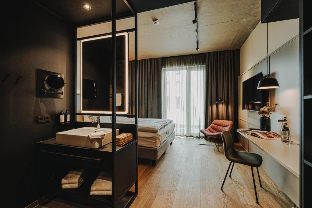 une chambre avec un lit, un lavabo et un miroir dans l'établissement HIIVE Oldenburg, à Oldenbourg