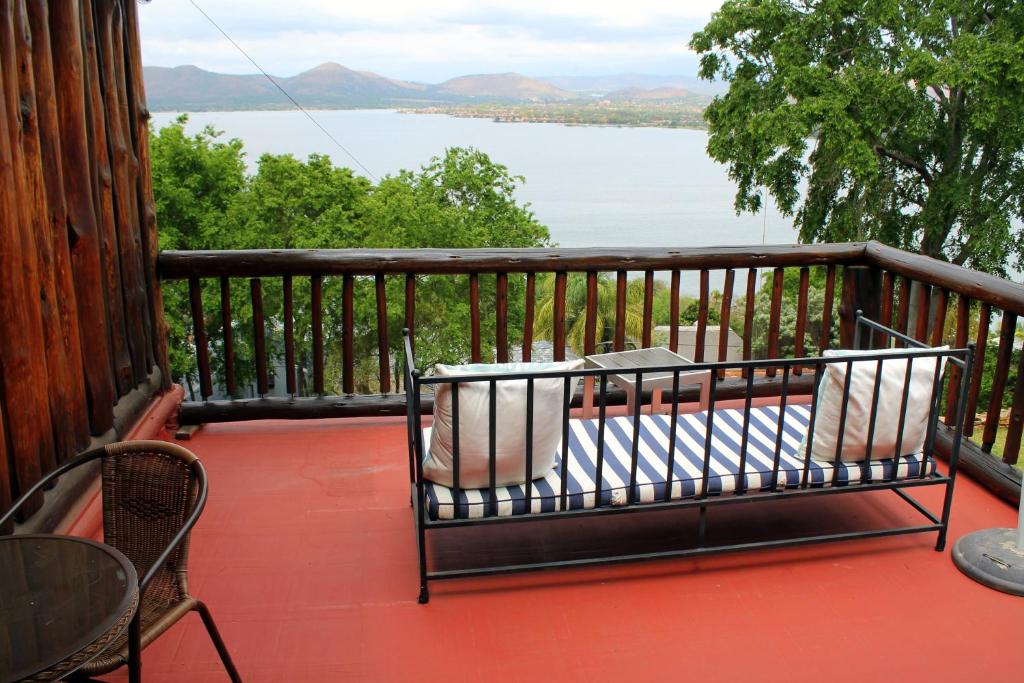 a balcony with a bench and a view of a lake at Hartbeespoortdam Lodge in Hartbeespoort