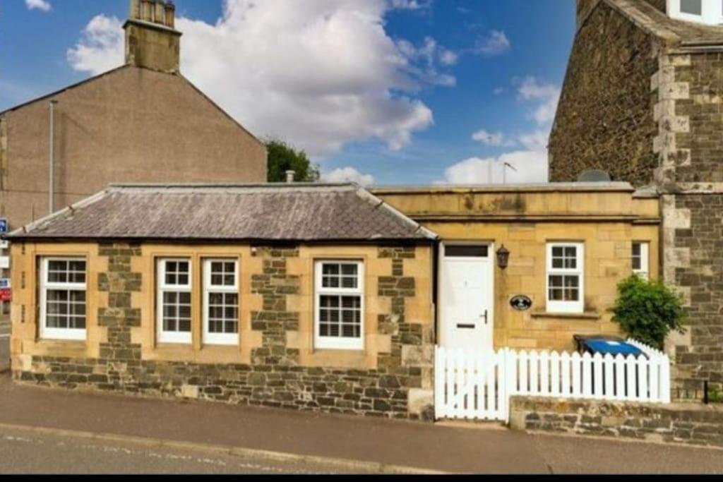 un pequeño edificio de ladrillo con una valla blanca en Crossways Cottage Quirky 2 bedroom cottage in Central location, en Peebles