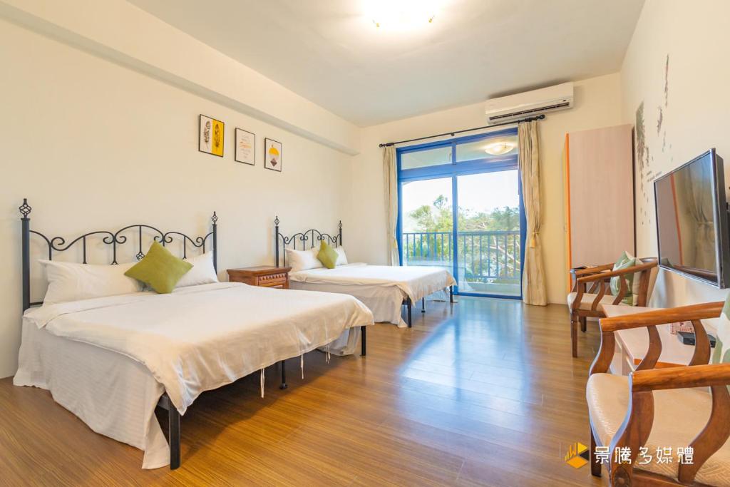 a bedroom with two beds and a balcony at Promised Land B&amp;B in Taitung City
