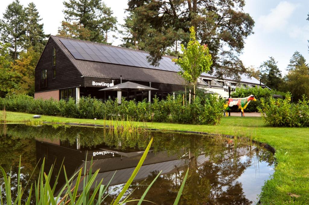 un granero negro con un reflejo en un estanque en Bosrijk Ruighenrode, en Lochem