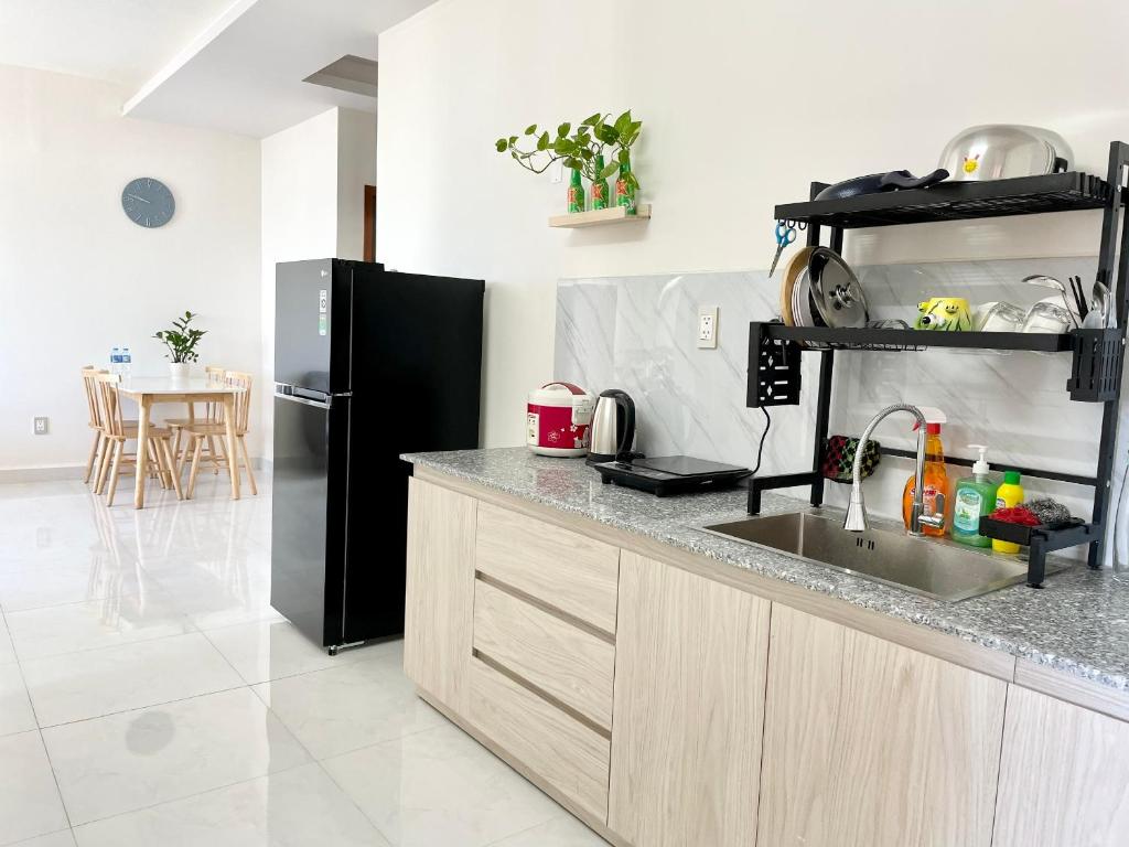 een keuken met een spoelbak en een zwarte koelkast bij Mayhome Phan Rang - 2BR City view - 3km to beach in Kinh Dinh
