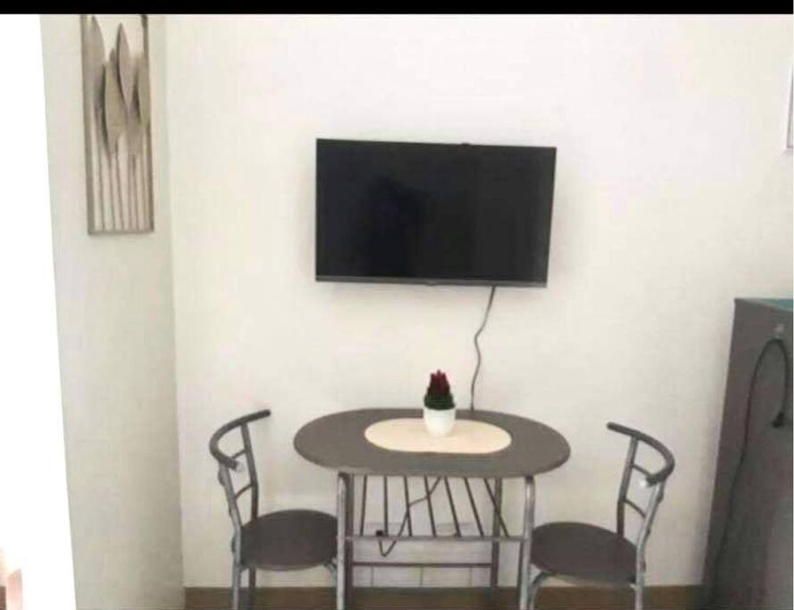 a table with chairs and a tv on a wall at Condo Unit 2 min away from Southmall, Las Pinas in Manila