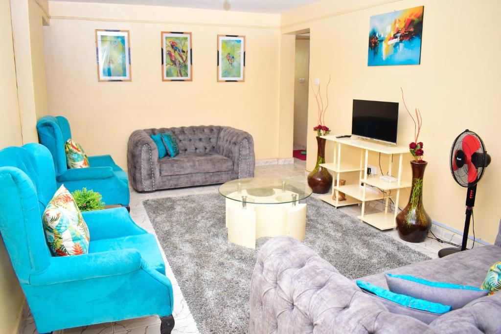 a living room with blue furniture and a tv at Rozie Apartment in Kisumu