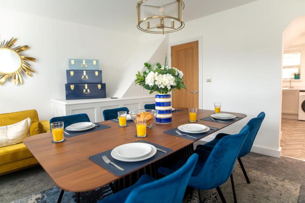 a dining room table with blue chairs and a vase of flowers at Harbour Heights in Folkestone