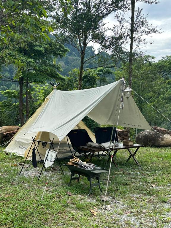 a tent with chairs and a table in a field at Moon hill camp in Kampong Egang