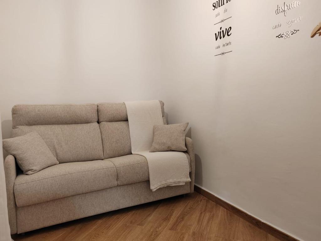 un sofá en una habitación con una pared blanca en Loreto 6, en Albacete
