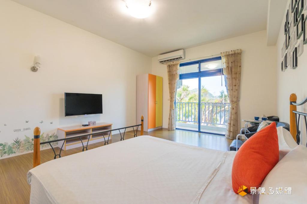 a bedroom with a bed and a tv and a balcony at Promised Land B&amp;B in Taitung City