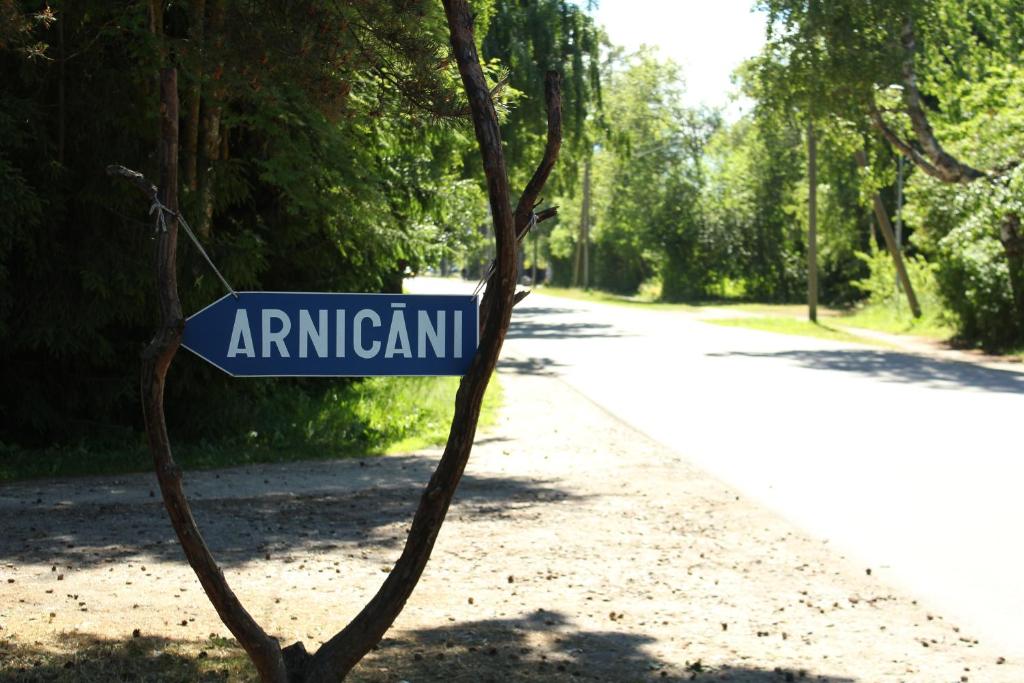 a street sign on a tree on the side of a road at Viesu Māja Arnicāni in Ragaciems