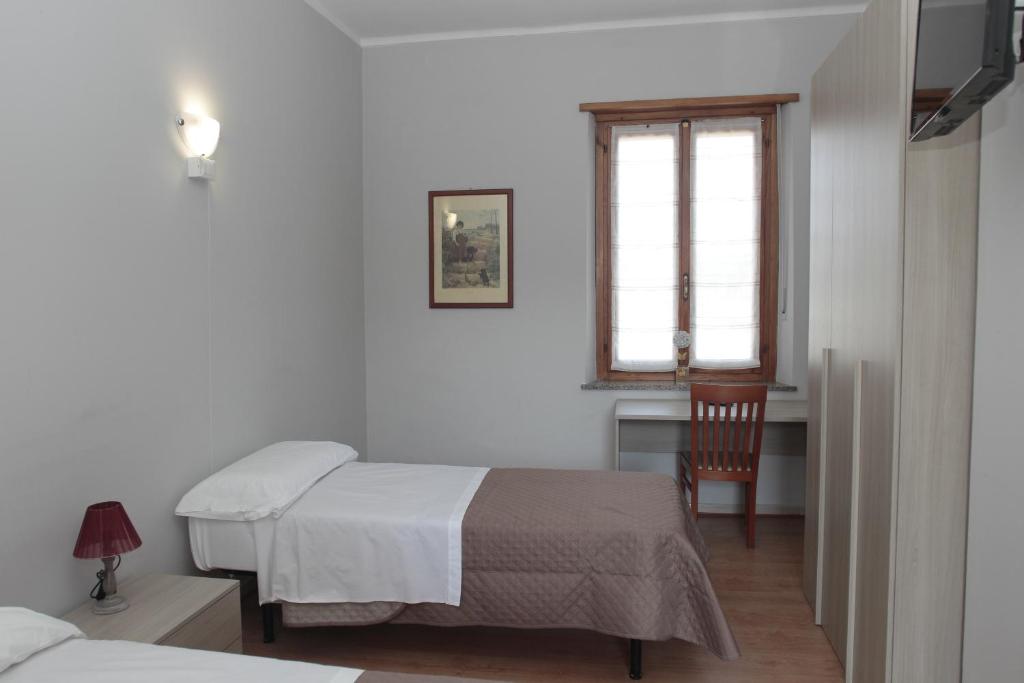 een slaapkamer met 2 bedden, een bureau en een raam bij La Porta del Sole in Caselle Torinese