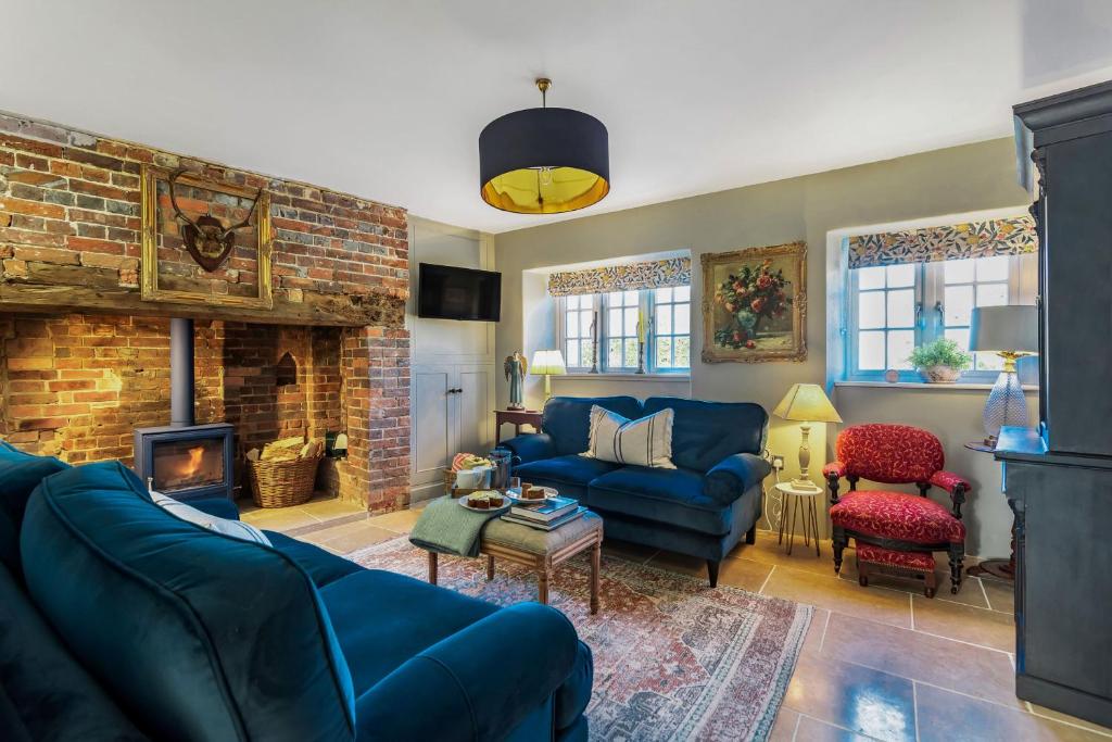 a living room with a blue couch and a fireplace at Little Dorset Cottage in Milton Abbas