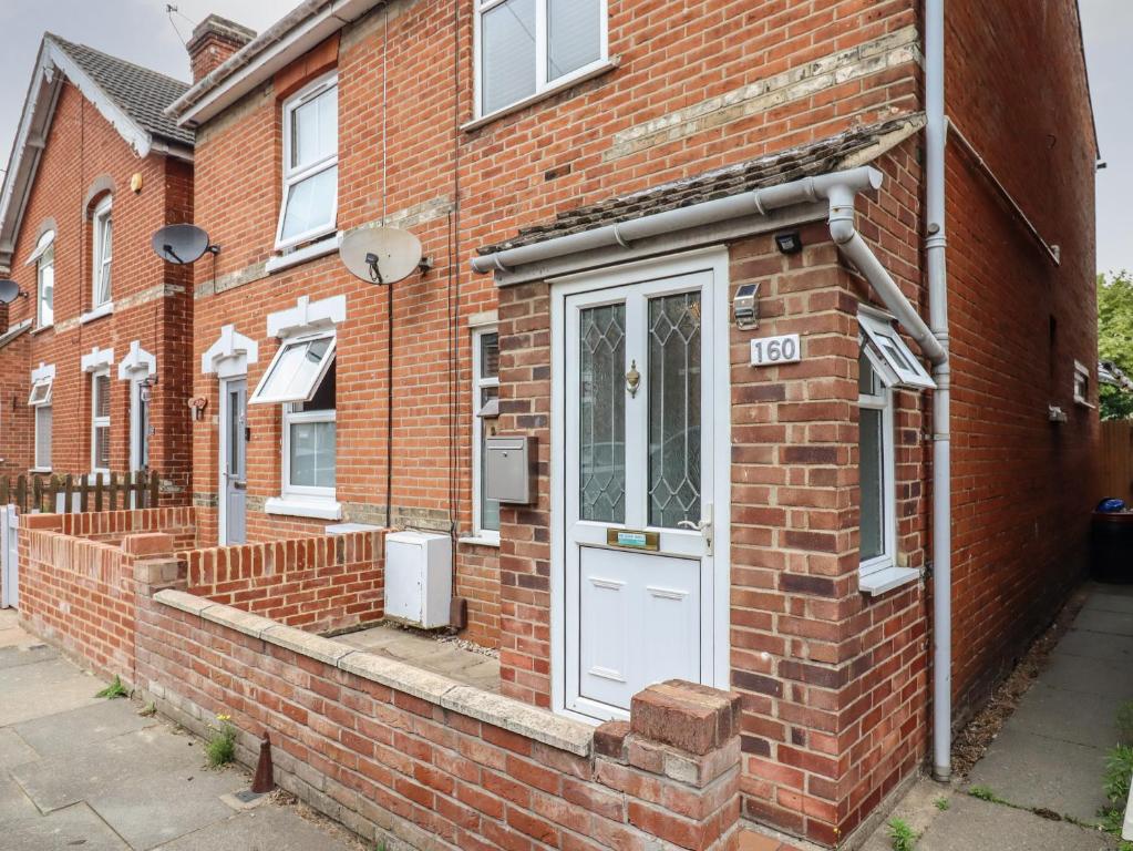 a brick house with a white door on a street at 160 Canterbury Road in Colchester