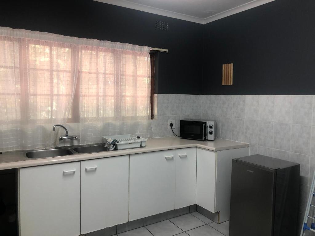 a kitchen with white cabinets and a sink and a microwave at Hillcrest/Waterfall Garden Hideaway! in Waterfall