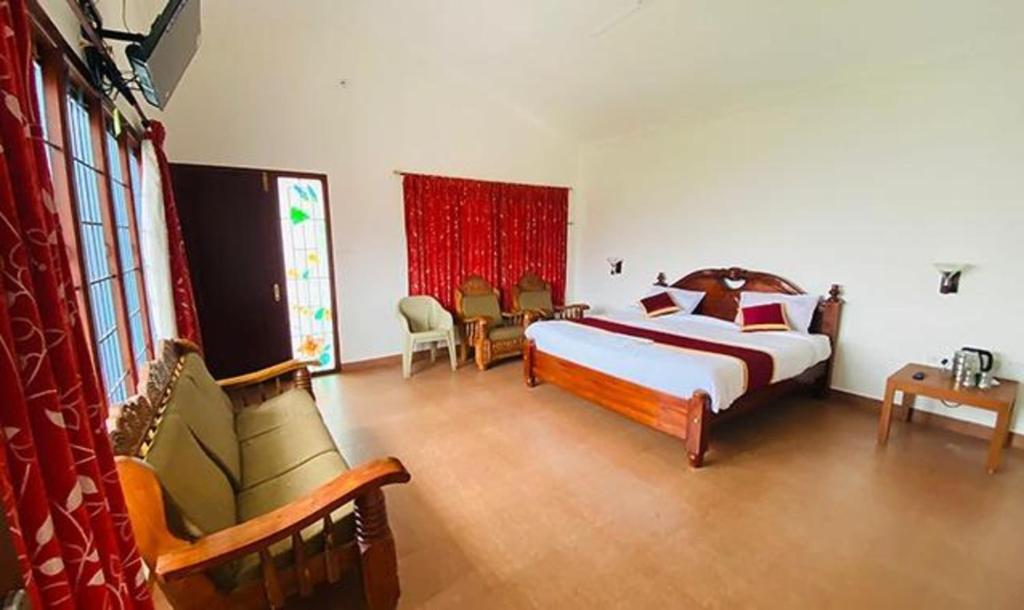 - une chambre avec un grand lit et des chaises dans l'établissement FabHotel Blossom Cottages, à Kodaikānāl