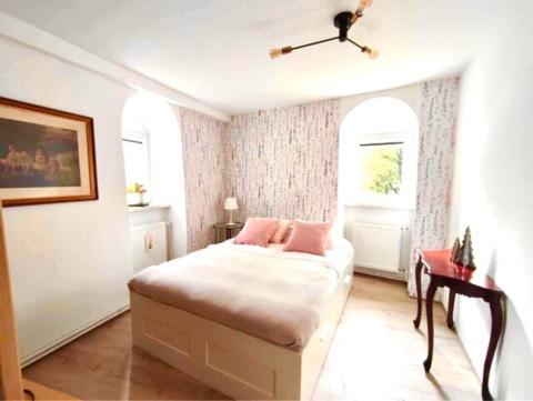 a white bedroom with a bed and a window at Apartament 44 in Lądek-Zdrój