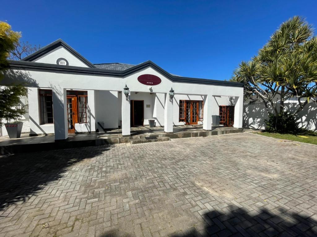 a white house with a brick driveway at Unique Guest House in Hallack Rock