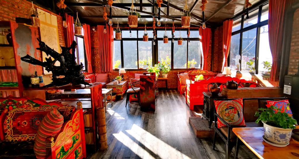 uma sala de estar com mesas, cadeiras e janelas em Kangding Guozhuang Nan Wu Hao Boutique Inn em Kangding