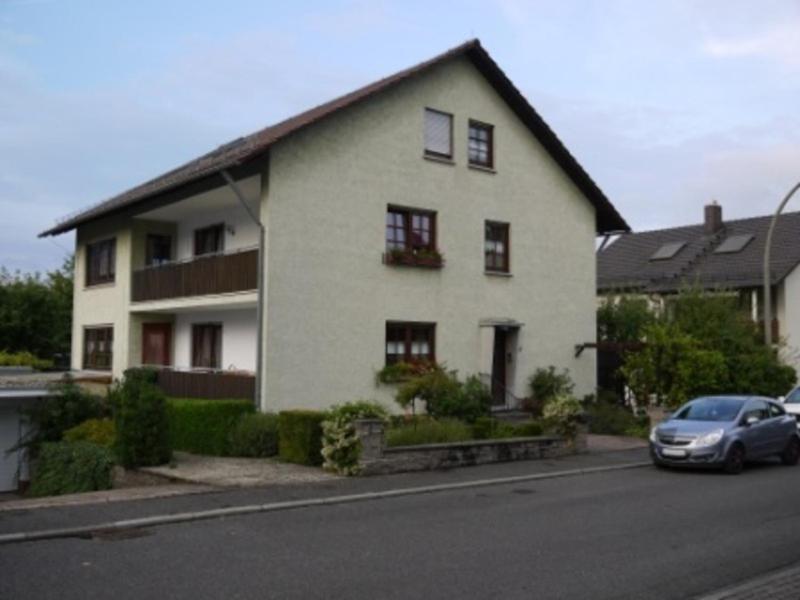 a white house with a car parked in front of it at Ferienwohnung Gisela Schmidt in Amorbach