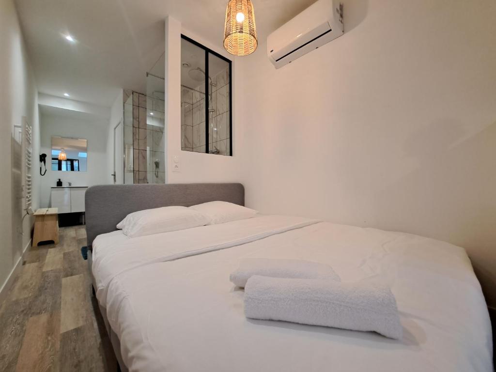 a bedroom with a white bed with towels on it at Maputo - Appartement climatisé in Reims