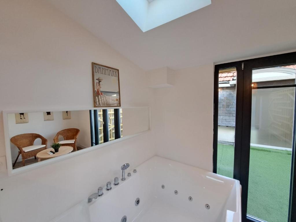 a white bathroom with a tub and a mirror at Maputo - Appartement climatisé in Reims