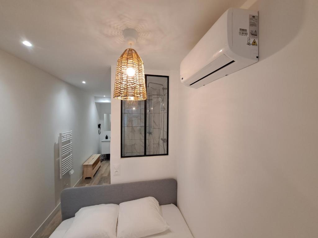 a living room with a couch and a light fixture at Maputo - Appartement climatisé in Reims