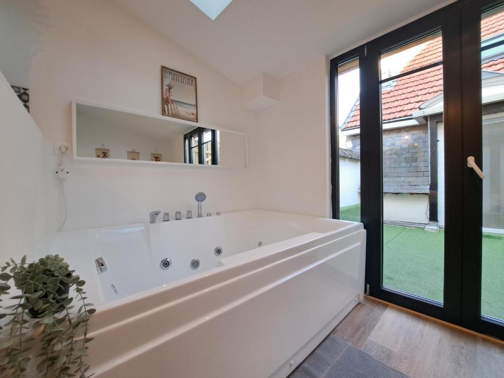 a white bathroom with a large tub and a window at Maputo - Appartement climatisé in Reims