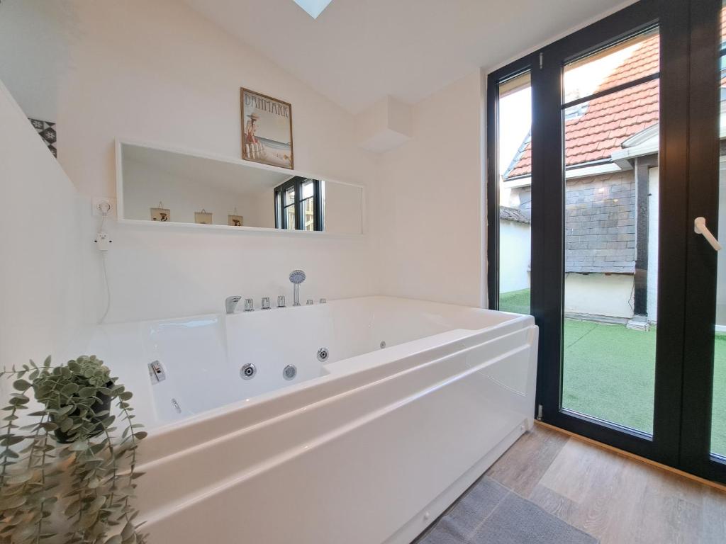 a white bathroom with a large tub and a window at Maputo - Appartement climatisé in Reims