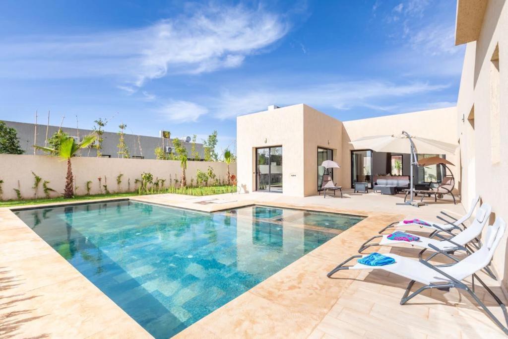 a villa with a swimming pool and lounge chairs at Luxury stylish 3suits villa in Marrakesh