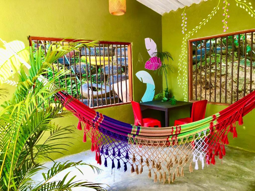 a hammock in a room with a table and chairs at Sierra Kay Hostel in Guachaca
