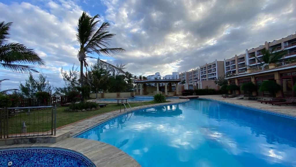 una gran piscina azul con palmeras y edificios en Lux Suites Eden Seafront Apartments, en Shanzu