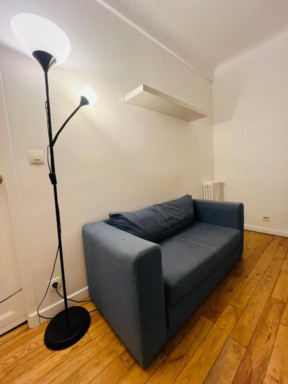 - un canapé bleu dans le salon avec une lampe dans l'établissement Stationnement Gratuit, 3mn du Métro, Parfait pour Télétravailler, à Maisons-Alfort