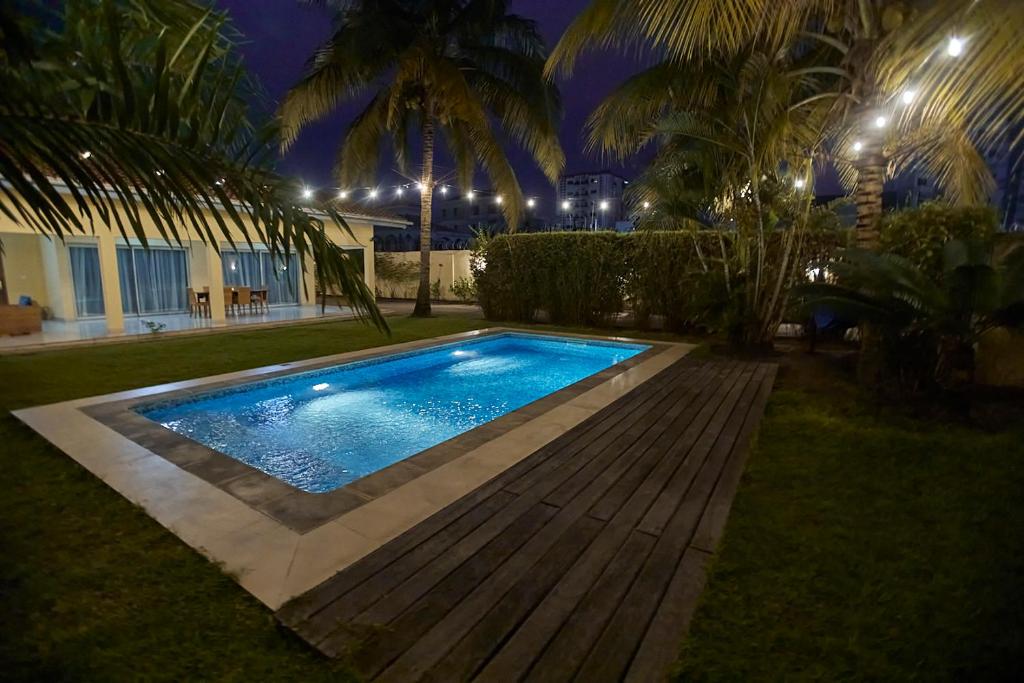 a swimming pool in a yard at night at Sompteuse villa avec piscine à 5 min de la plage in Pointe-Noire