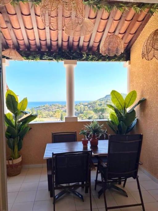 une salle à manger avec une table et des chaises et une grande fenêtre dans l'établissement Cap Esterél studio vue mer 5 pers premium place, à Saint-Raphaël