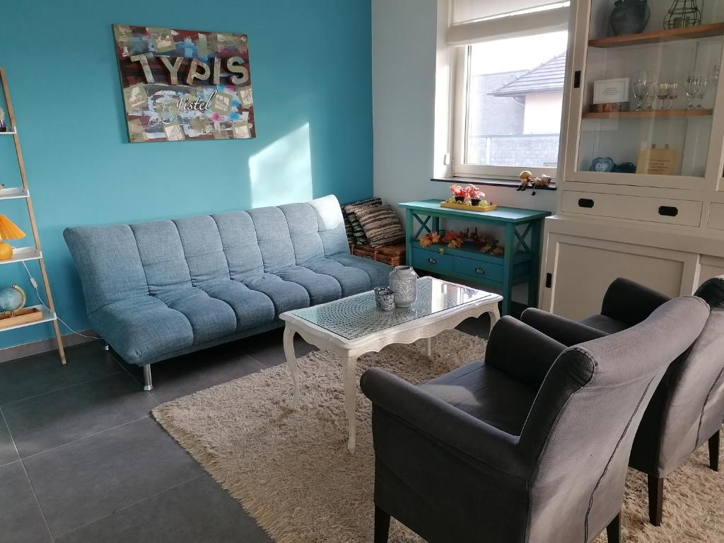 ein Wohnzimmer mit einem blauen Sofa und Stühlen in der Unterkunft TypisGistel in Gistel