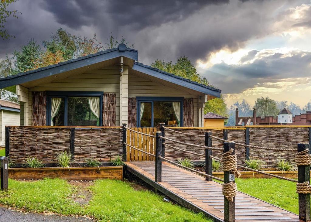 a house with a wooden deck and a fence at Sherwood Castle Holiday Forest in Edwinstowe