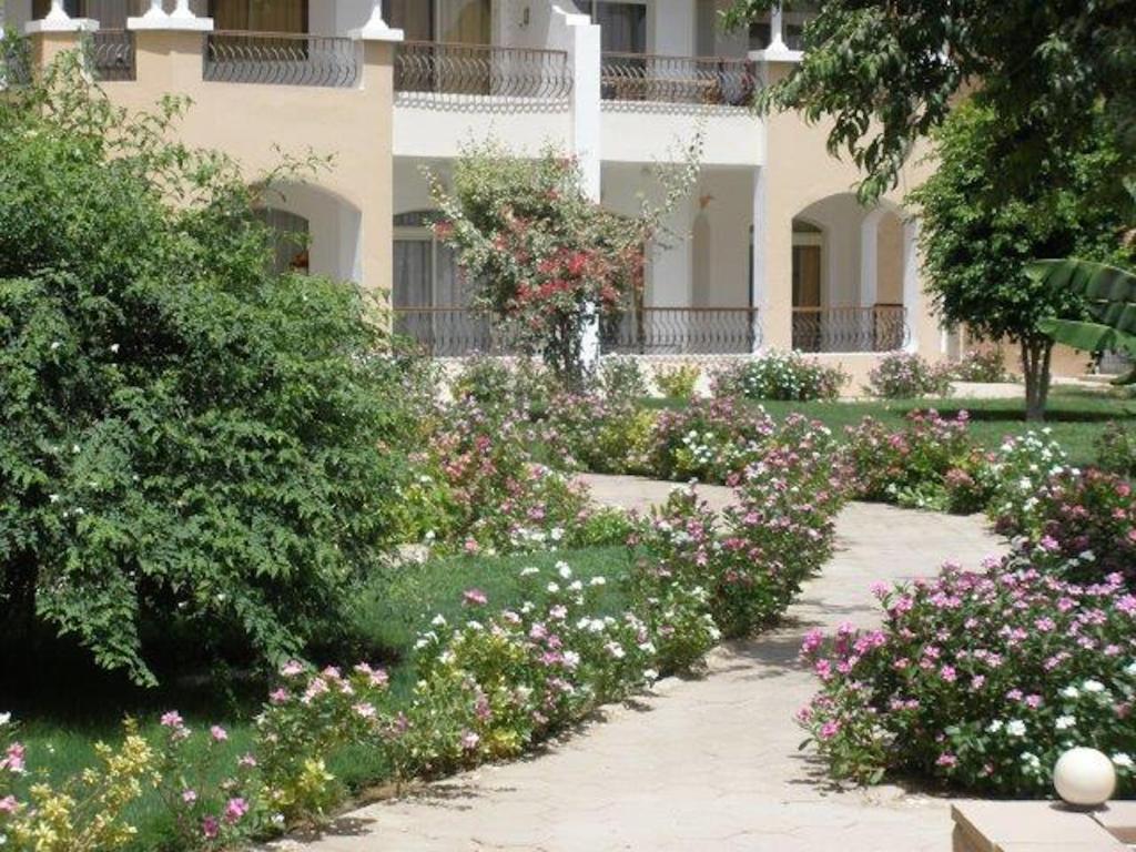 a garden with flowers in front of a building at Dream Away Luxor in Al Marīs