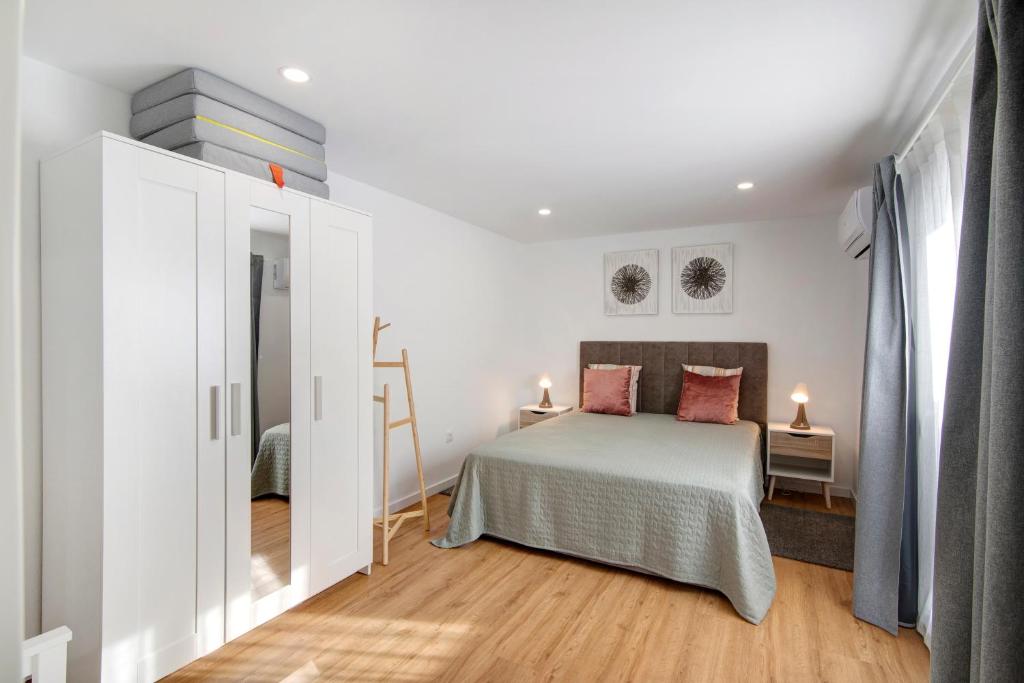 a white bedroom with a bed and a window at Telmus Villa Rc D in Monte Gordo