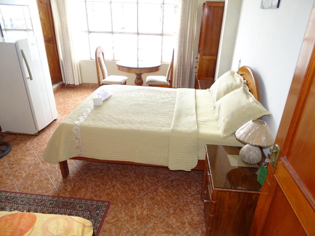 Schlafzimmer mit einem Bett, einem Tisch und einem Fenster in der Unterkunft HOSTAL RESIDENCIAL UCAYALI in Tingo María