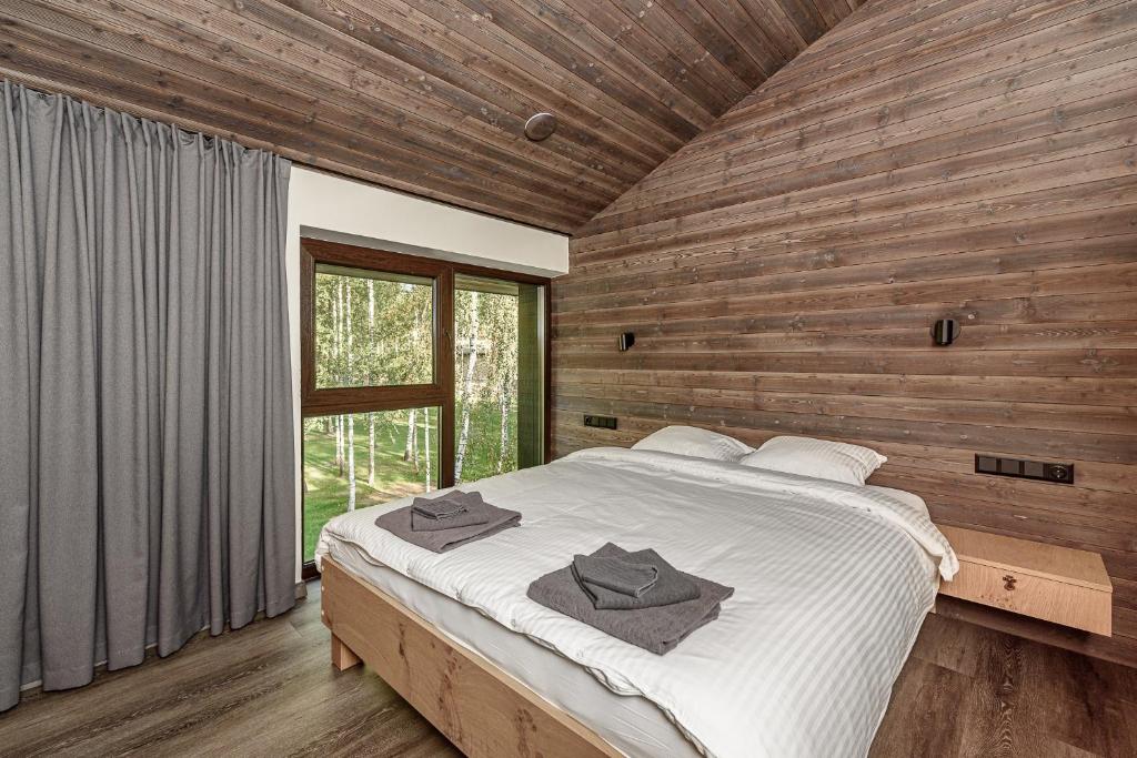 1 dormitorio con 1 cama grande y toallas. en Ranča, en Molėtai