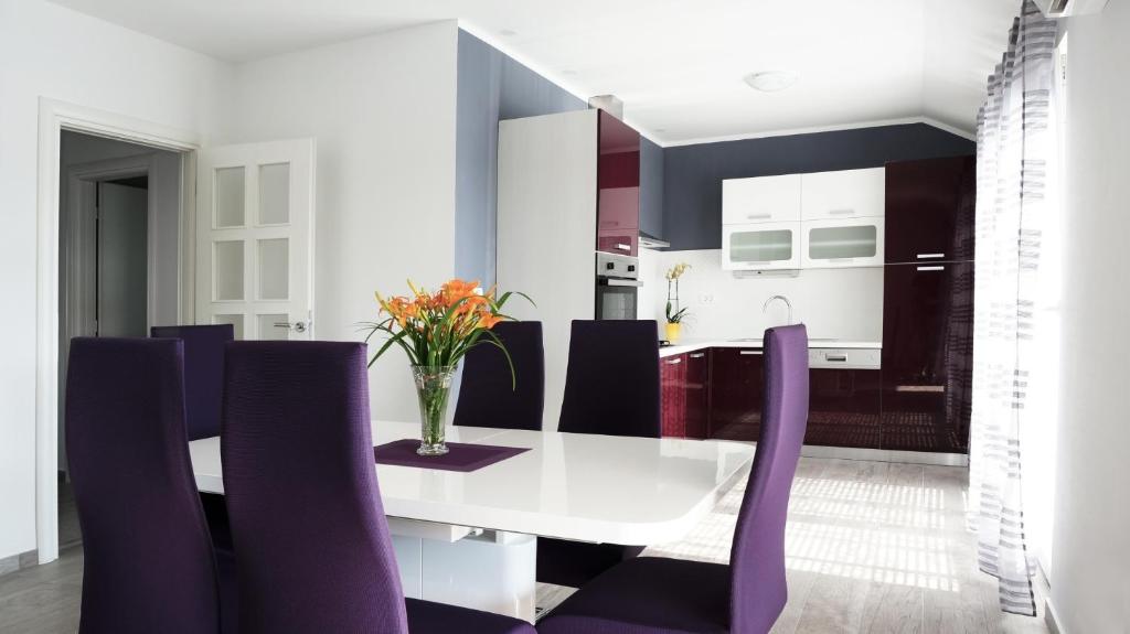 a dining room with a white table and purple chairs at Apartment L&A in Grebaštica