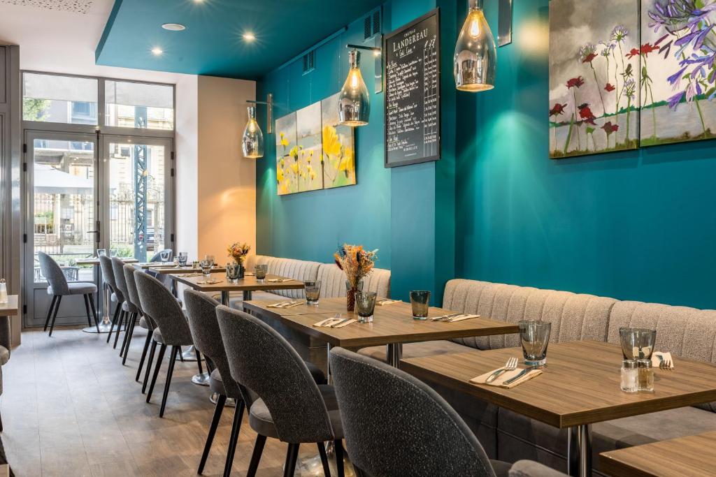 une rangée de tables dans un restaurant aux murs bleus dans l'établissement Hotel-Restaurant Le Victoria, à Rennes